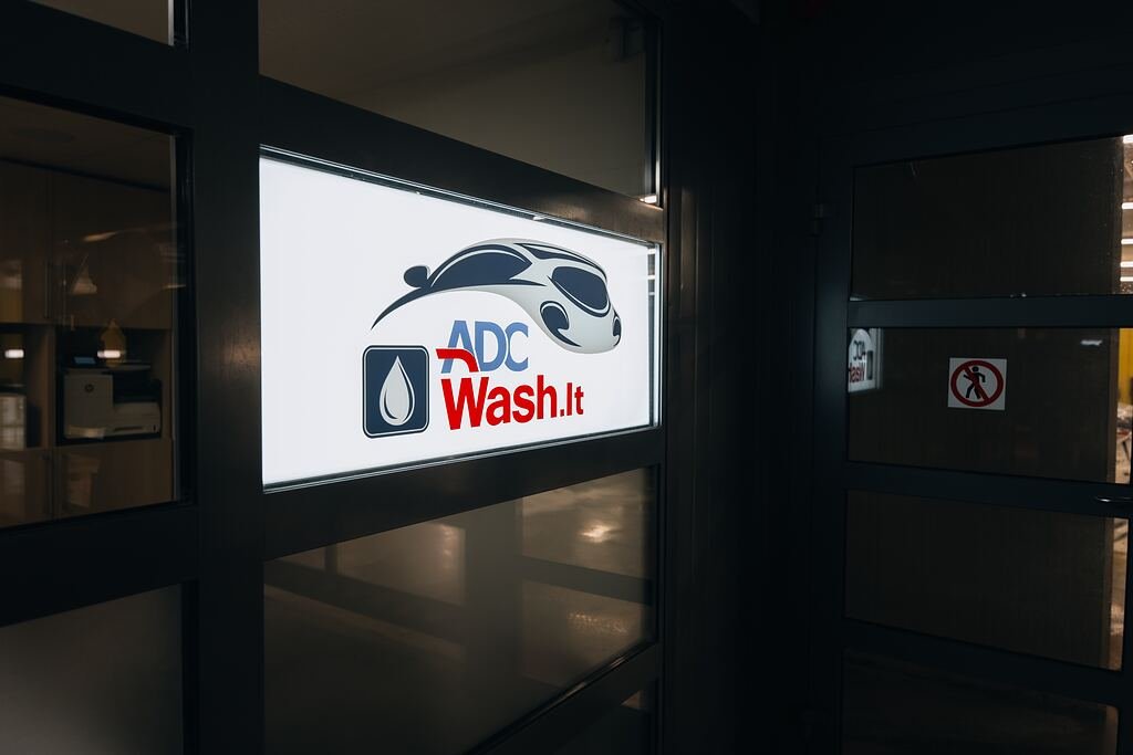 Apšviesta ADCWash.lt iškaba prie plovyklos įėjimo daugiaukštėje aikštelėje